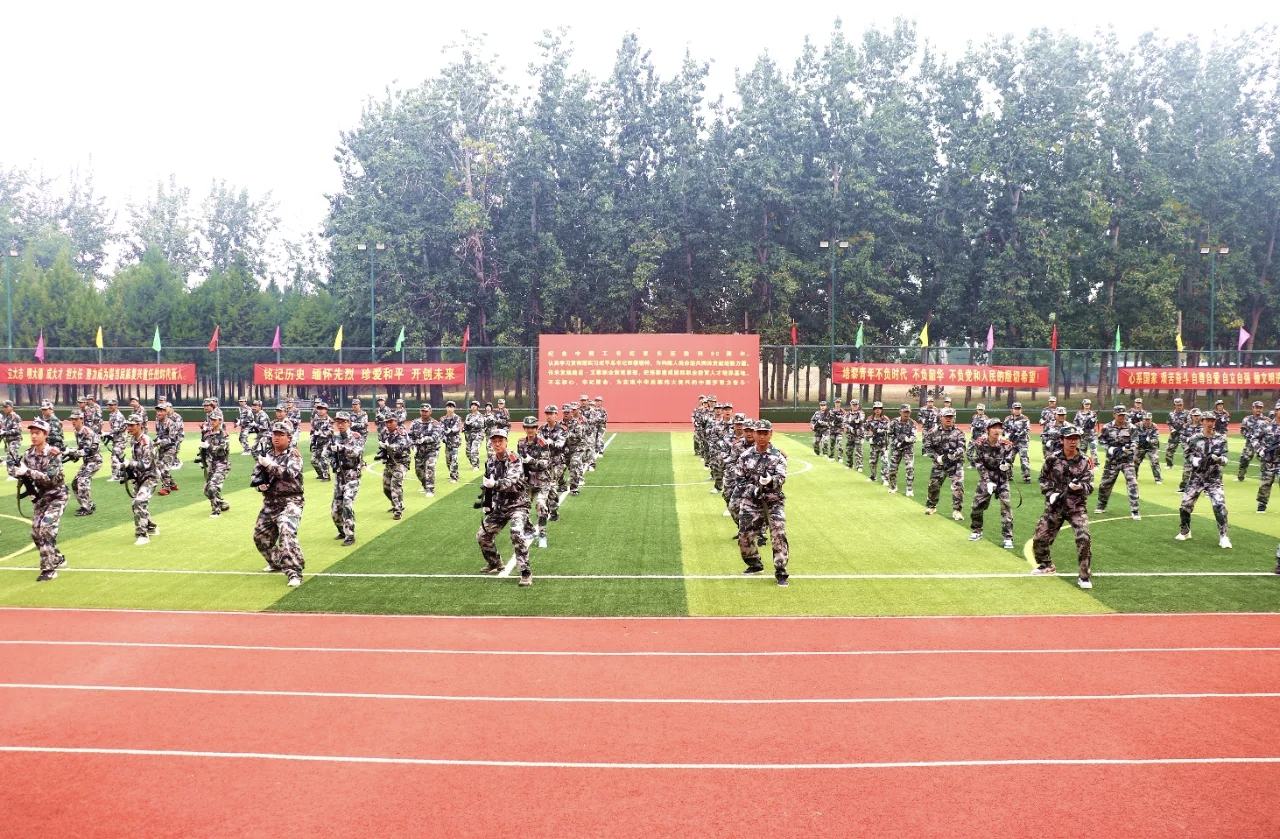 照片：北京培黎职业学院 2026级新生军训结训仪式暨开学典礼——新生分列式方队正经过主席台，迷彩队列整齐，身后红色背景板印有仪式全称（学院官方微信文章配图，2026-09-19 收录）