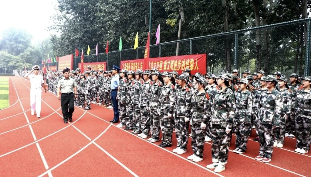 照片：军训结训仪式检阅环节——承训教官沿跑道行进检阅，新生方队整齐列队，场边悬挂红色标语（学院官方微信文章配图，2026-09-19 收录）