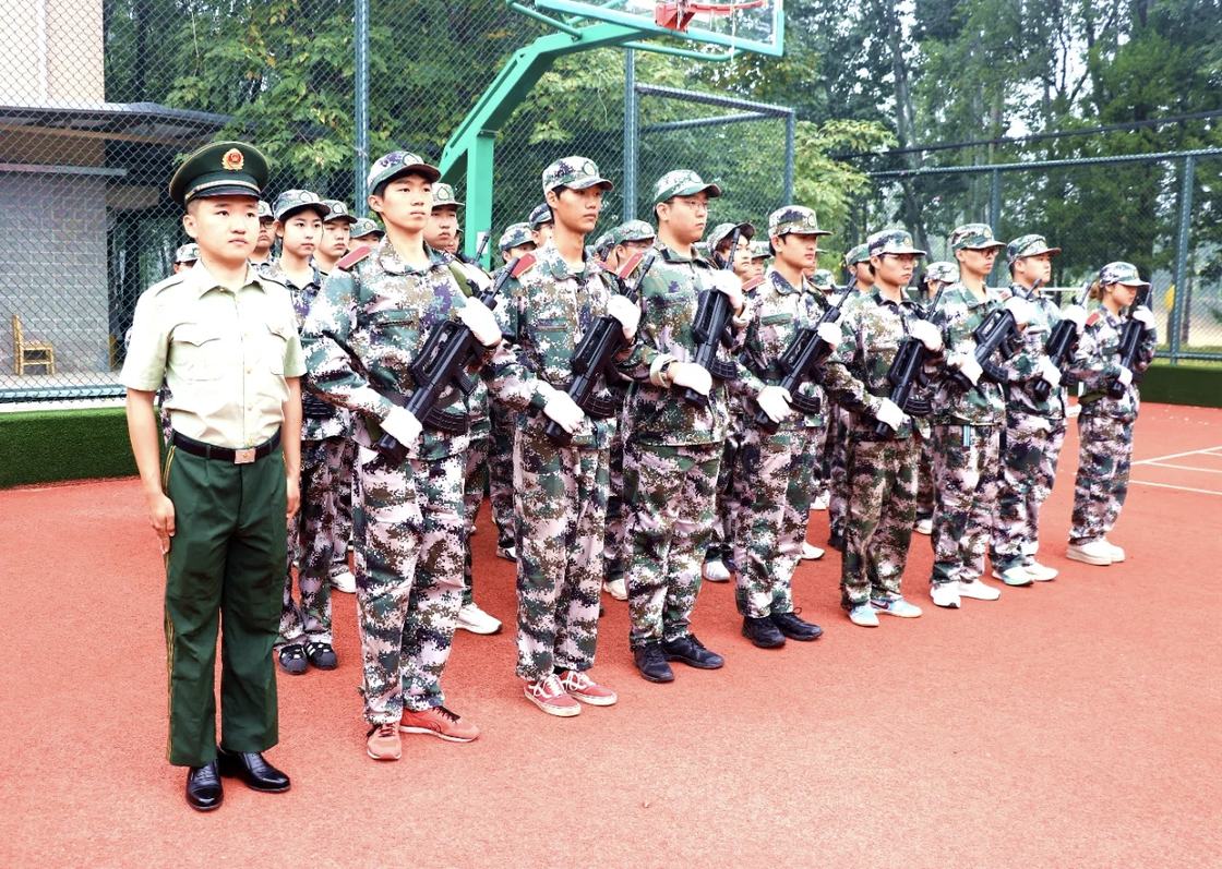 照片：军训结训仪式现场——新生方队持系旗在各连队列前肃立待命，场边彩旗与红色标语横幅展开（学院官方微信文章配图，2026-09-19 收录）